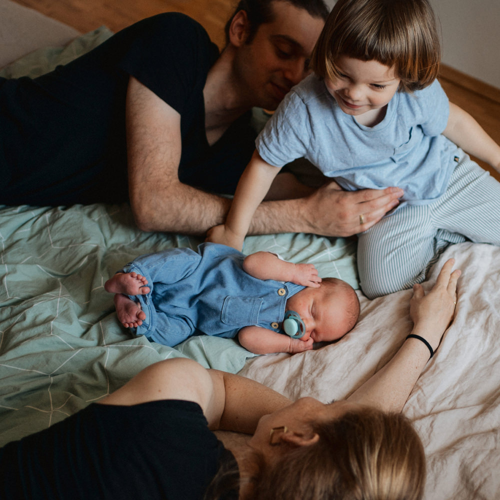 Familie mit Neugeborenem im Wochenbett zu Hause