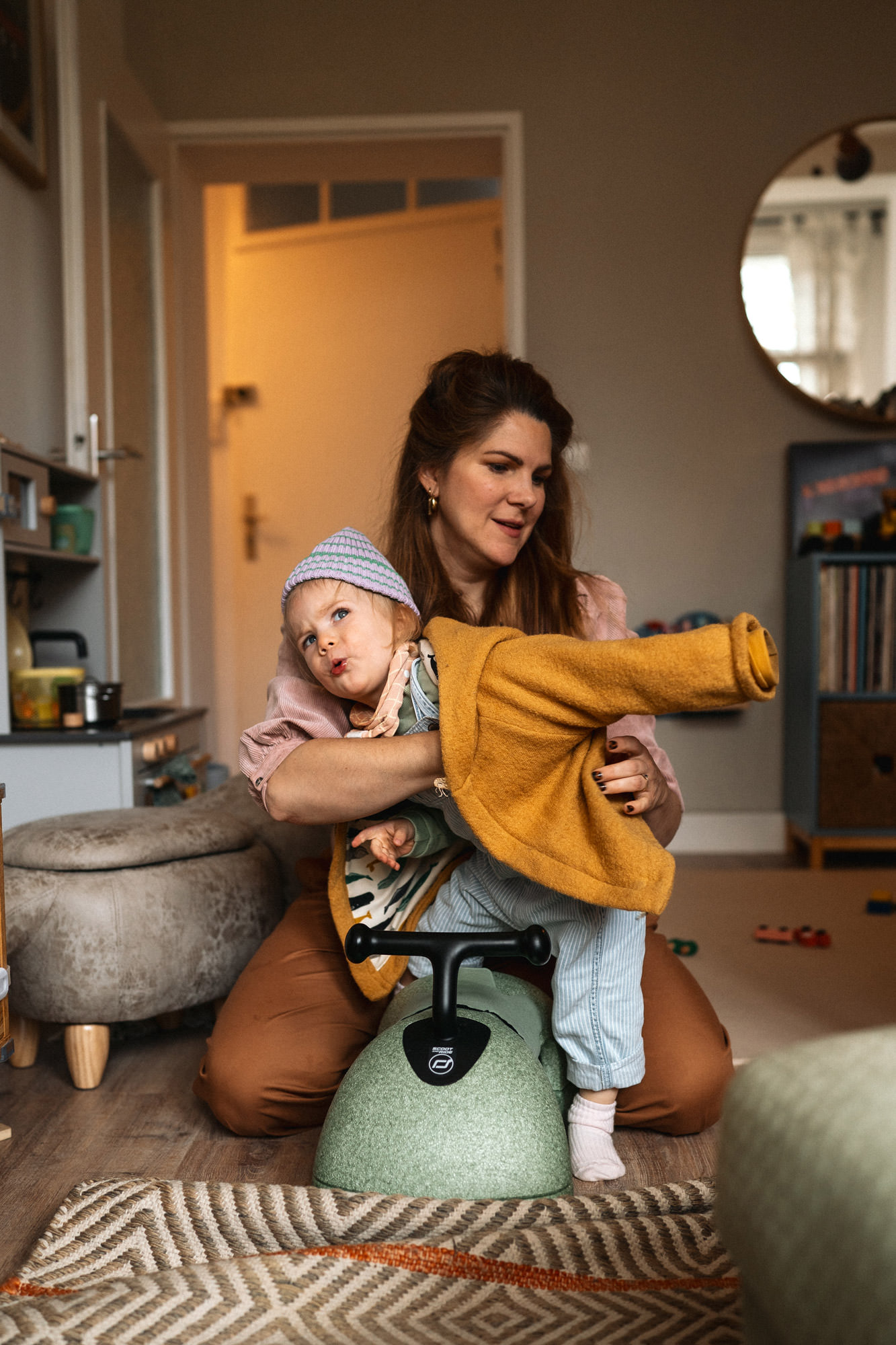 Mutter zieht Kind in der Wohnung in Köln die Walkjacke an