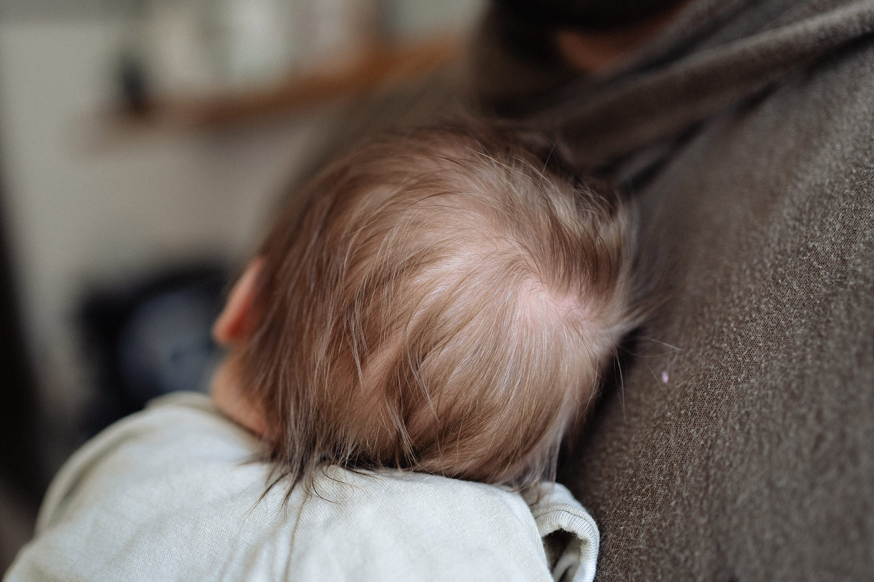 Schlafendes Neugeborenes im Wochenbett, behutsam gehalten in ruhiger Atmosphäre