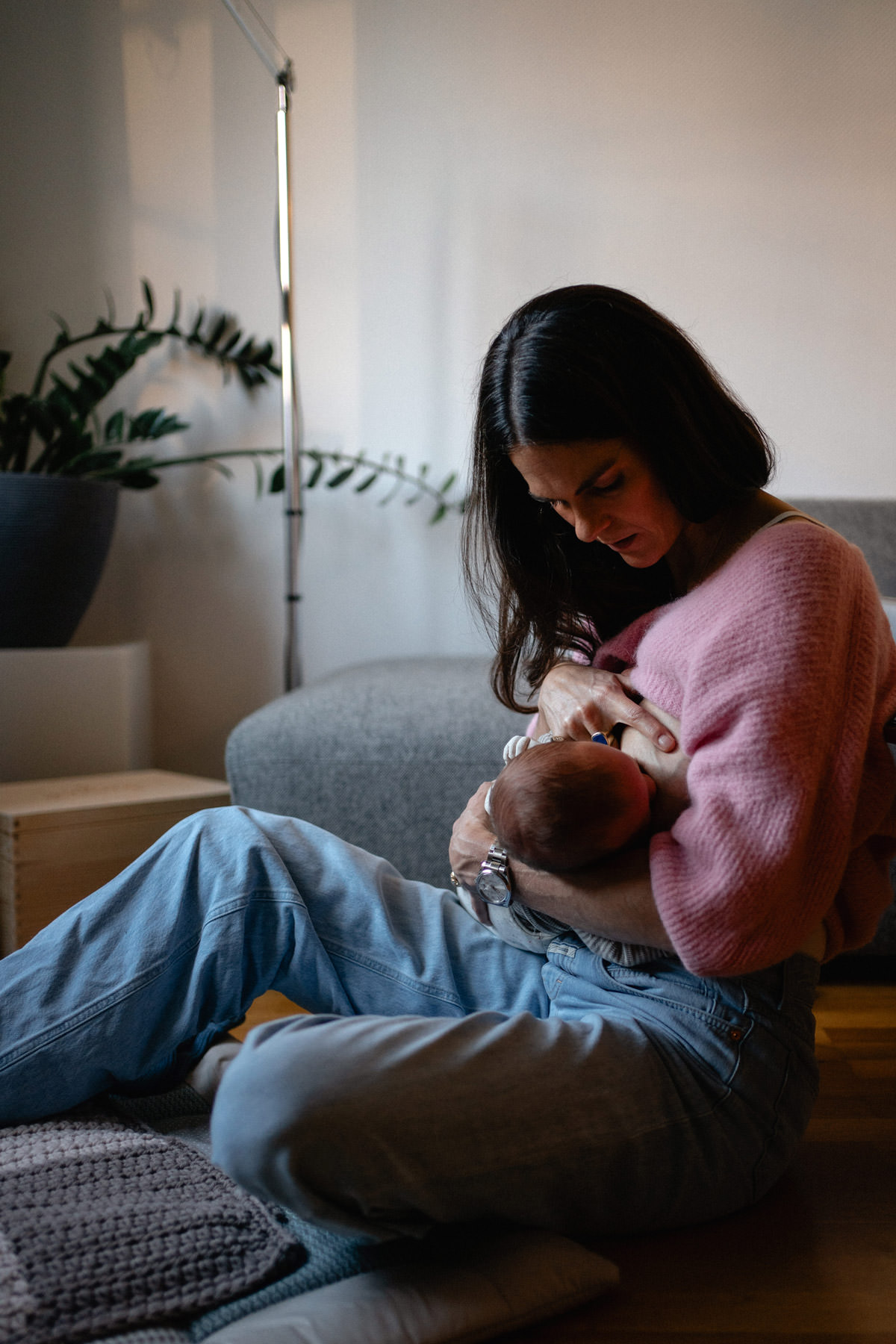 Inniger Stillmoment im Wochenbett, Mutter sitzt entspannt mit Baby zu Hause