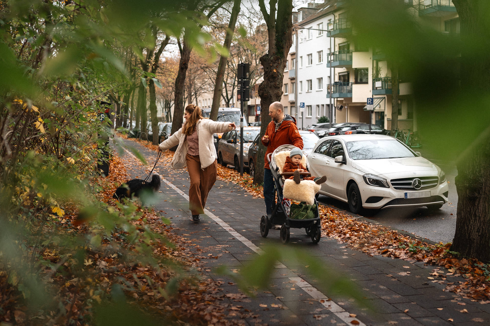 Familie geht spazieren mit Kinderwagen und Hund