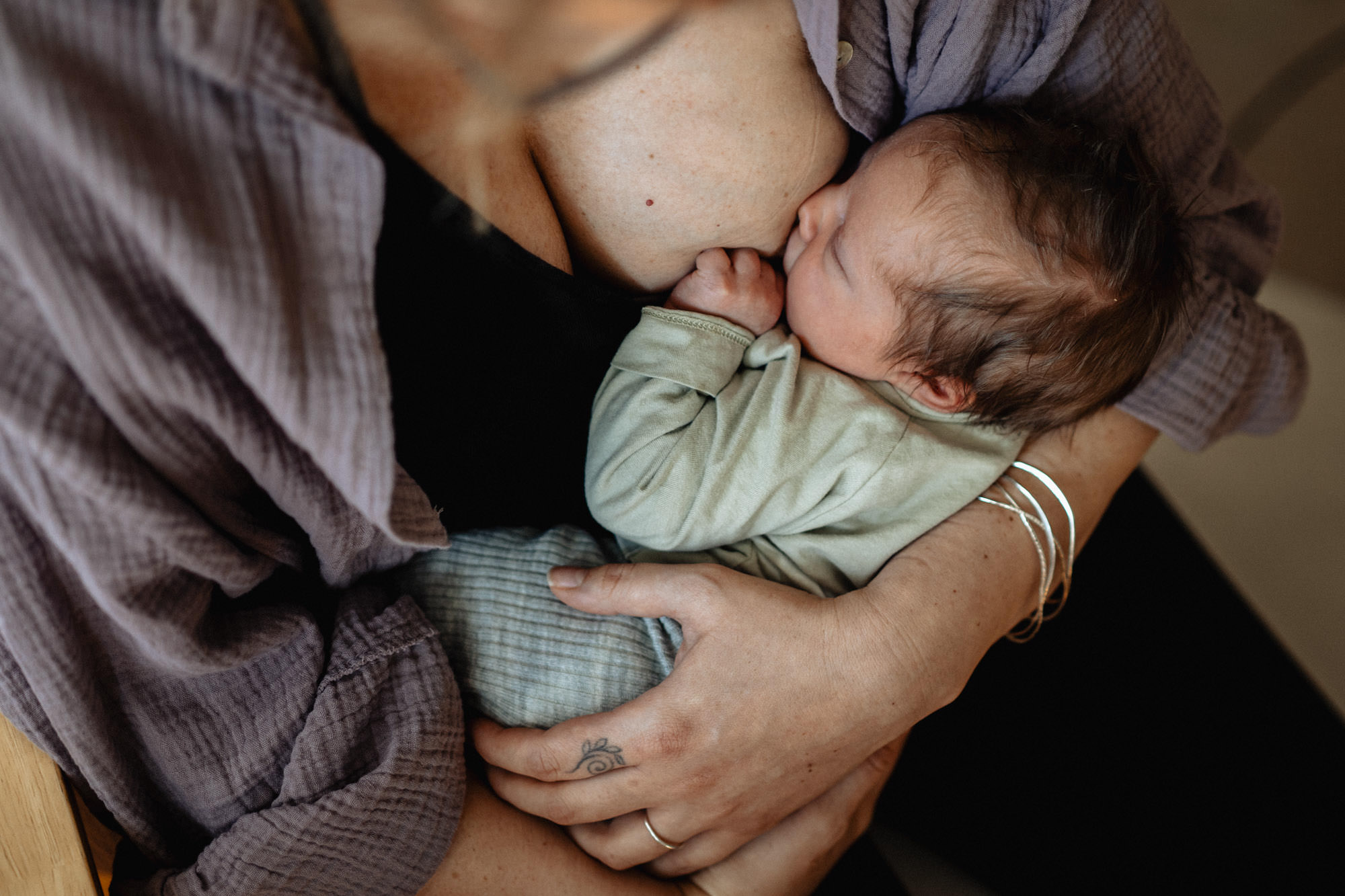 Neugeborenes liegt auf dem Arm der Mutter und wird gestillt