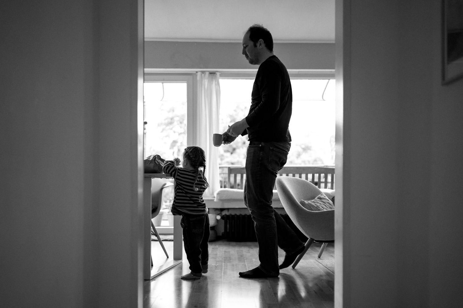 Vater geht mit Kind zum Tisch und deckt den Frühstückstisch