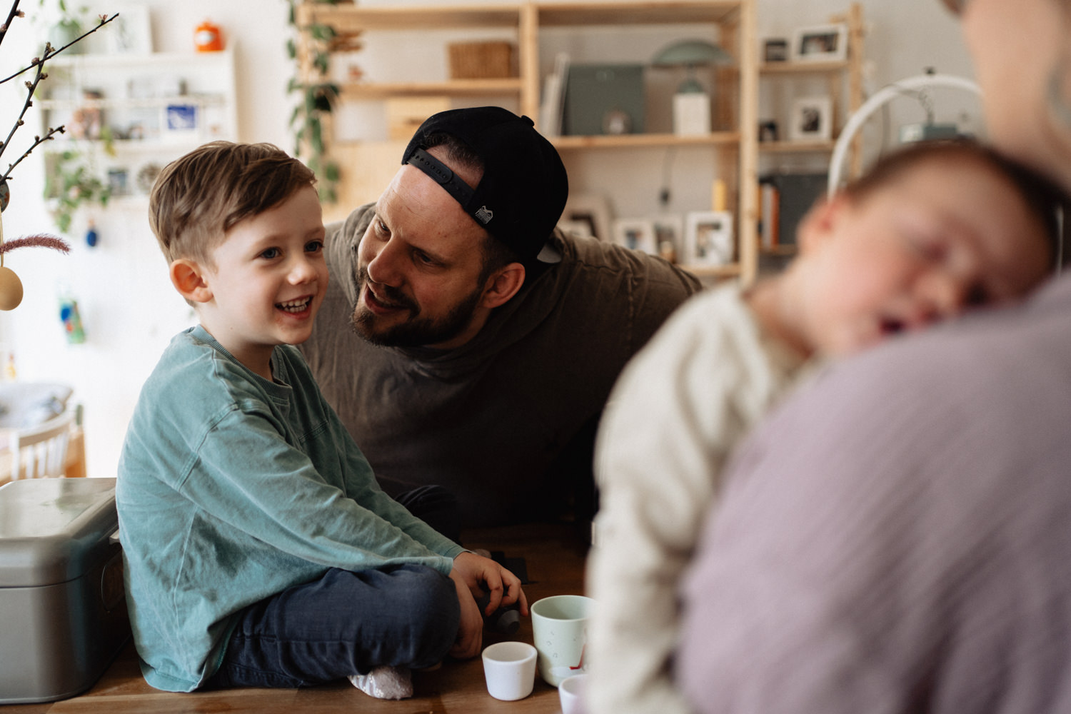 Vater schaut Sohn an. Baby auf Arm im Vordergrund