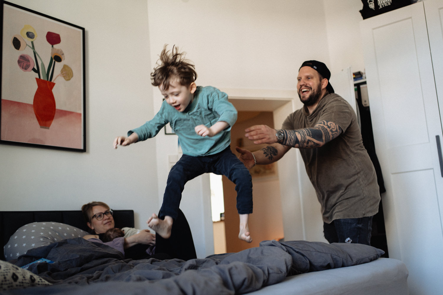 Vater wirft Sohn aufs Bett, Mutter und Baby liegen daneben